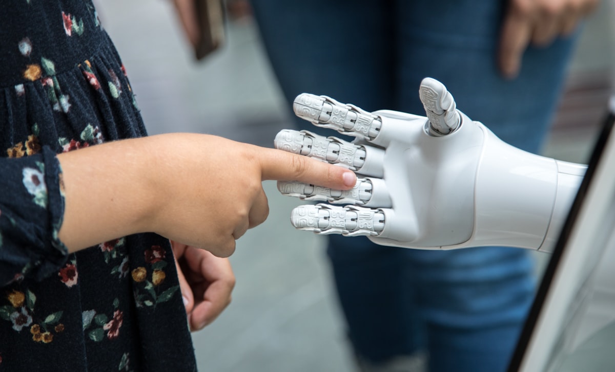 A person holding a robotic hand, representing the intersection of technology and humanity